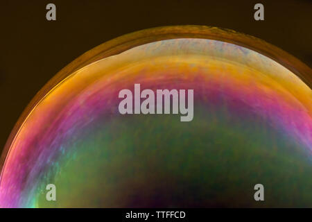 Couleurs arc-en-ciel reflétées dans bulle de savon coloré sur zone noire Banque D'Images