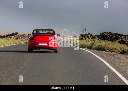 Cabrio rouge voiture vide route pavée dans les paysages volcaniques du désert Banque D'Images