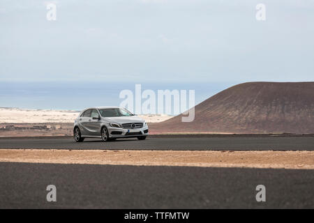 Voiture grise vide conduite route pavée dans les paysages volcaniques du désert Banque D'Images