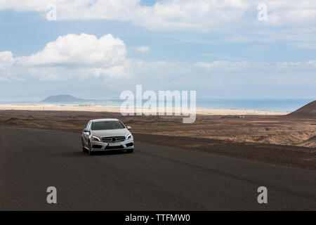 Voiture grise vide conduite route pavée dans les paysages volcaniques du désert Banque D'Images