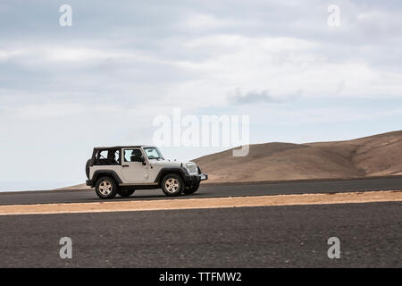 Voiture grise vide conduite route pavée dans les paysages volcaniques du désert Banque D'Images