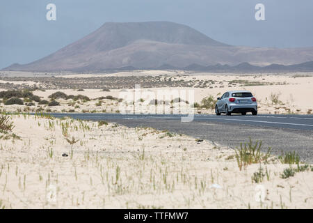 Voiture grise vide conduite route pavée dans les paysages volcaniques du désert Banque D'Images