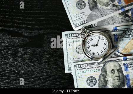 Le temps est argent concept avec montre de poche et en dollars sur les factures, vue de dessus de table en bois Banque D'Images