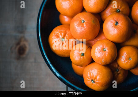 Close up of bowl de mandarines sur table en bois tourné à partir de ci-dessus. Banque D'Images