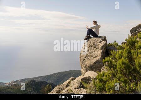 Vue de côté de l'homme à la montagne tout en vue à contre ciel lors de journée ensoleillée Banque D'Images