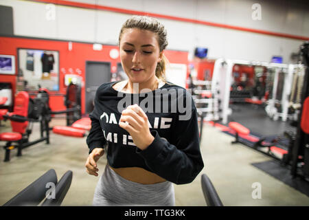 Femme à la voiture tandis que l'exercice sur tapis roulant dans une salle de sport Banque D'Images