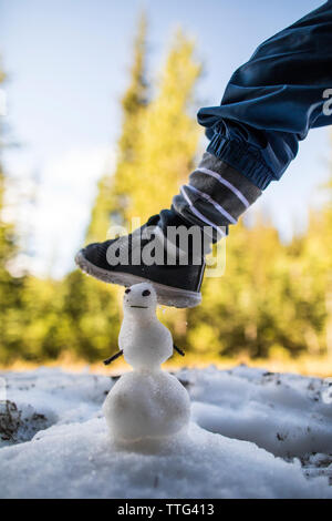 Bébé garçon marche sur le bonhomme de neige miniature. Banque D'Images