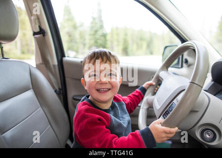 Petit garçon faisant semblant de conduire voiture Banque D'Images