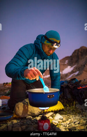 Mountaineer cuire un repas sur une cuisinière ultra-léger dans les montagnes. Banque D'Images