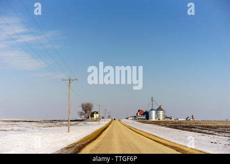 Route droite avec voiture dans l'hiver Midwestern farm country Banque D'Images