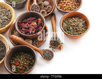 Variété de thé sec dans des pots et cuillères en bois isolé sur blanc Banque D'Images