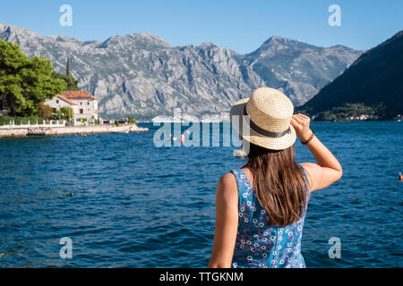 Vue arrière de woman in hat regarder la mer avec les montagnes