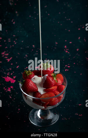 Les Fraises et la crème dans un bol en verre Banque D'Images