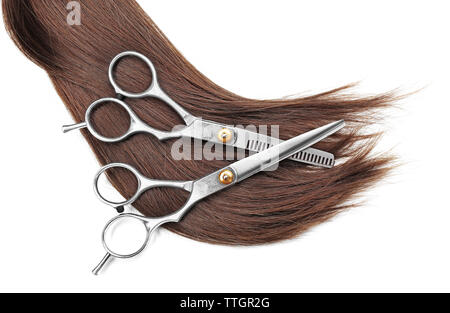 Ciseaux de coiffure avec mèche de cheveux bruns, isolated on white Banque D'Images