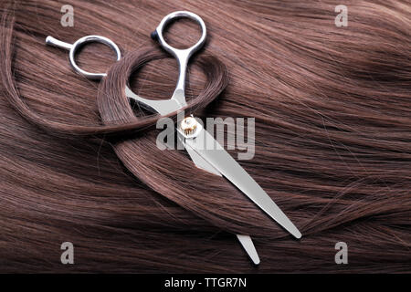 Ciseaux de coiffure avec des cheveux bruns foncés, Close up Banque D'Images