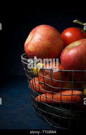 Close-up de fruits avec des légumes en panier métal sur table Banque D'Images