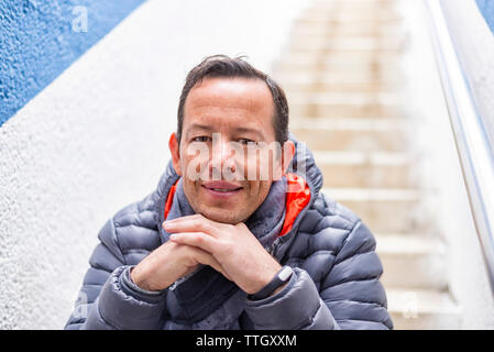 Thoughtful businessman with hands on chin assis sur un escalier Banque D'Images