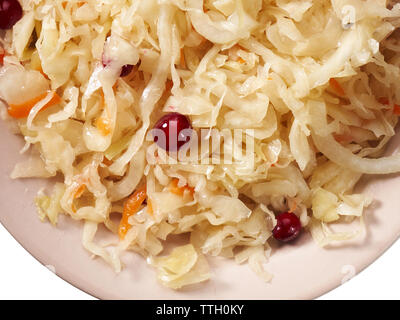 La choucroute avec des canneberges dans une assiette sur un fond blanc. Banque D'Images