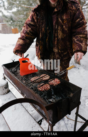 L'homme pour les hamburgers frites magrets. barbecue Banque D'Images