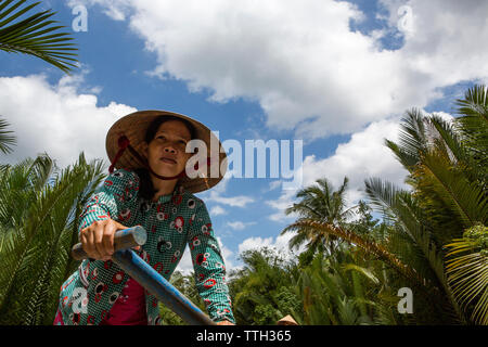 Les palettes d'une femme un bateau sur un canal dans le Delta du Mekong, Vietnam. Banque D'Images