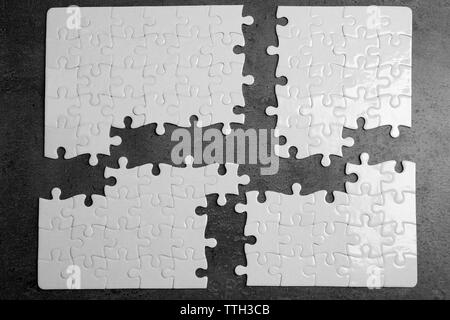 Quatre pièces de puzzle blanc avec pièces manquantes sur fond gris Banque D'Images