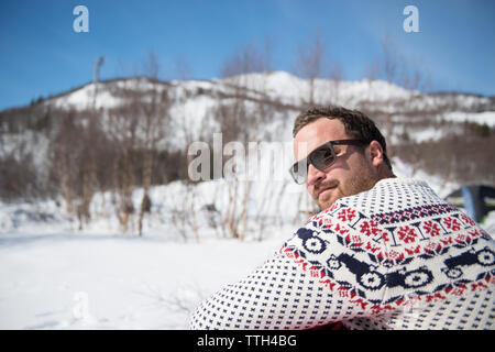 Smiling man dans les montagnes enneigées en hiver avec des lunettes Banque D'Images