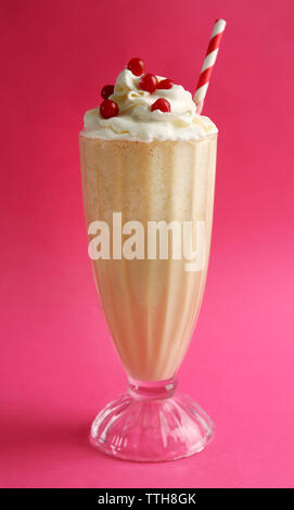 Verre de cocktail de lait avec de la crème et les baies sur fond rose Banque D'Images