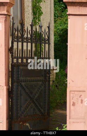 L'entrée et la porte de fer rouillée d'un vieux abandonnés et aperçu de villa avec un jardin sauvage. Banque D'Images