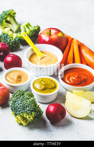 Des légumes et fruits (pomme purée de bébé, brocoli, carotte, prune) dans un bol blanc avec des ingrédients. Concept d'aliments pour bébés. Banque D'Images