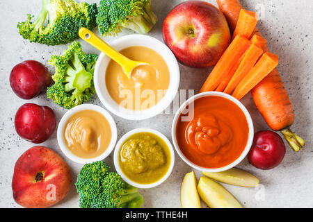 Des légumes et fruits (pomme purée de bébé, brocoli, carotte, prune) dans un bol blanc avec des ingrédients. Concept d'aliments pour bébés. Banque D'Images