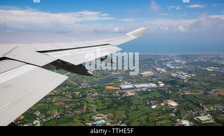 Vous voyagez par avion. Vue aérienne d'une ville à l'île de Taiwan. Voir l'aile de l'avion et la ville de Taoyuan en arrière-plan comme vu à travers une fenêtre. Banque D'Images