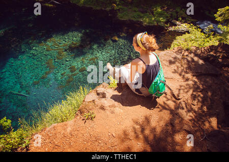 High angle view of female hiker sitting on rock against lake Banque D'Images