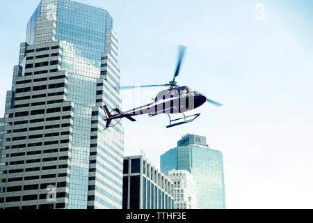 Low angle view of helicopter contre des immeubles modernes en ville Banque D'Images