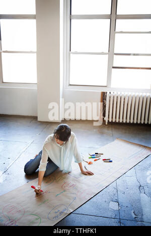 High angle view of businesswoman la préparation graphique tout en étant assis sur le plancher Banque D'Images