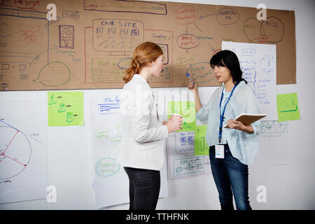 Plus de Businesswomen discussing charts alors que standing in office