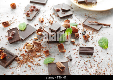 Morceaux de chocolat avec des noisettes et de la menthe fraîche sur fond clair Banque D'Images