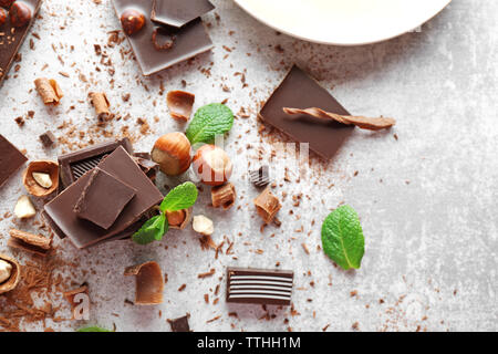 Morceaux de chocolat avec des noisettes et de la menthe fraîche sur fond clair Banque D'Images