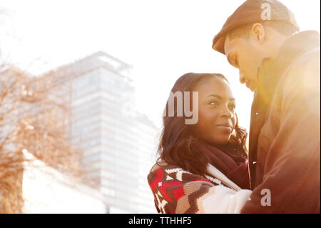 Low angle view of young couple contre les bâtiments aux beaux jours Banque D'Images