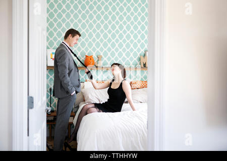 Femme passionnée de l'homme tirant en cravate à la maison de chambre à coucher Banque D'Images
