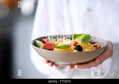 Chef hands holding délicieux salade de pâtes froides dans un bol closeup Banque D'Images