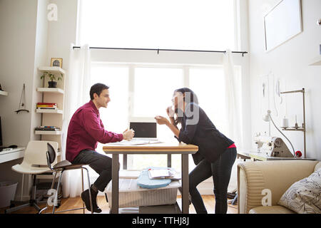 homme d'affaires ayant la discussion avec une collègue féminine à table dans le bureau créatif Banque D'Images