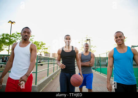 Portrait of happy friends avec le basket-ball marche sur sentier en park Banque D'Images