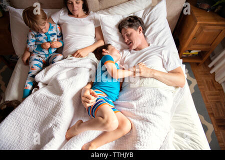 Vue de dessus de parents avec enfants se trouvant sur le lit chez lui Banque D'Images