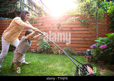 La mère et le fils de la tonte de l'herbe dans la cour avant Banque D'Images