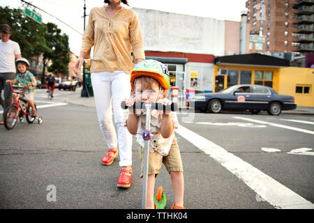 Portrait of boy riding scooter push avec la famille dans les rues en ville Banque D'Images