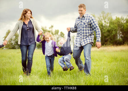 Heureux les enfants dont les parents bénéficiant on grassy field Banque D'Images