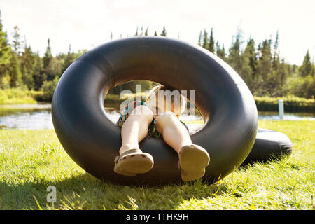 Garçon jouant avec anneau gonflable on grassy field Banque D'Images