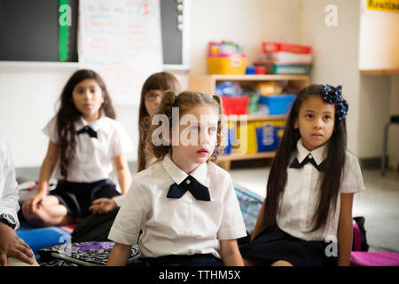 Ecolières sitting on floor in classroom Banque D'Images