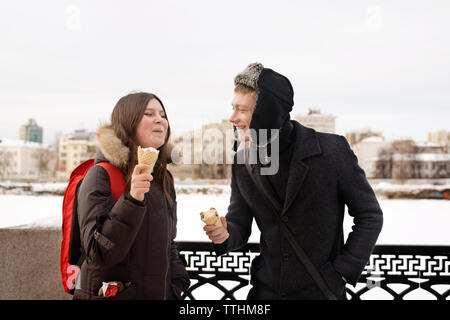 Couple heureux de manger de la glace en hiver à park Banque D'Images