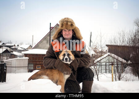 Portrait d'homme avec chien sur le terrain couvert de neige Banque D'Images